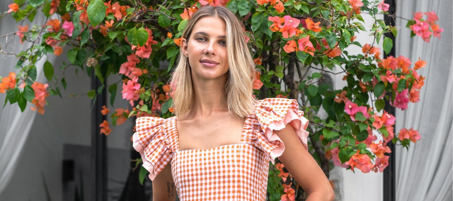 woman wearing gingham dress in front of flowers
